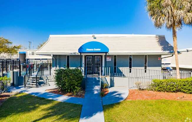 the front of a building with a blue roof and a porch with a palm tree  at The Park at Chesterfield Apartment Homes, Tampa, Florida