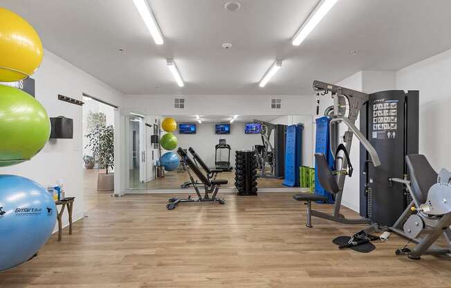 a gym with cardio equipment and weights on a wooden floor