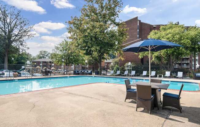 A pool with chairs and an umbrella in the foreground.