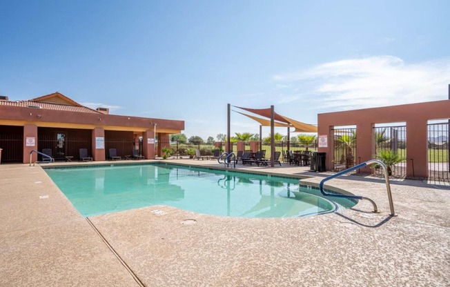 The pool is surrounded by a sundeck with lounge chairs at Village Greens of Queen Creek