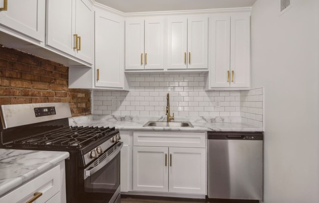 a kitchen with white cabinets and a brick wall