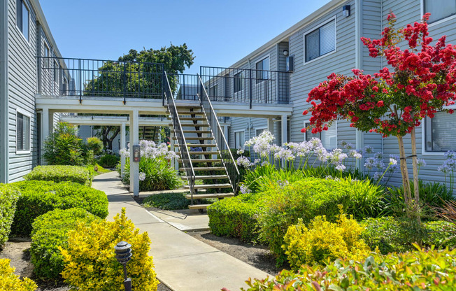 a staircase leading to an apartment building with a garden in front of it