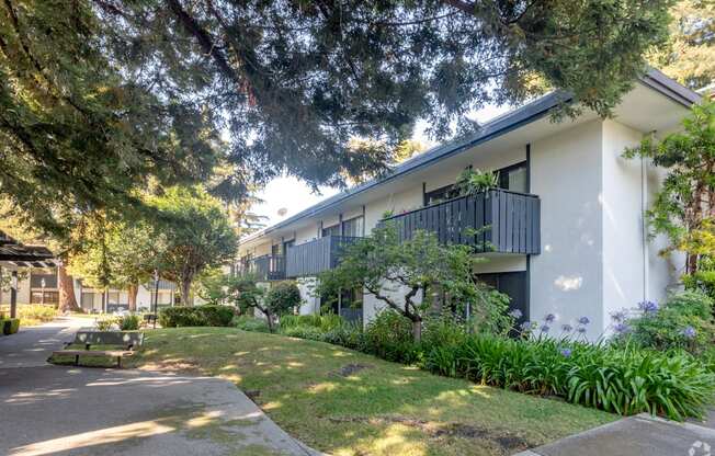 an apartment building with a lawn and trees in front of it