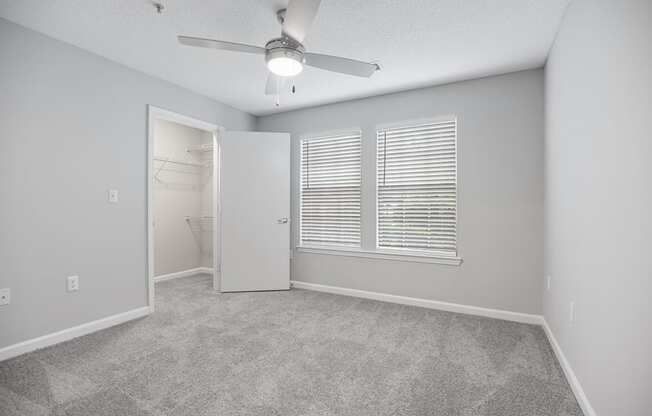 an empty bedroom with a ceiling fan and a bathroom