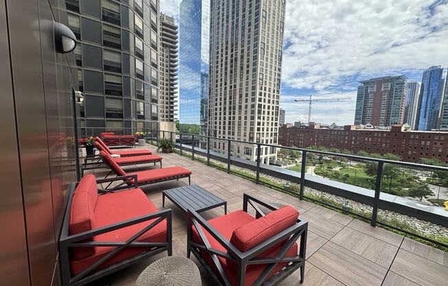 a balcony with red chairs and a view of skyscrapers