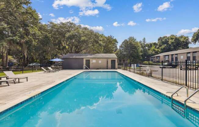 A swimming pool surrounded by trees and a building in the background.