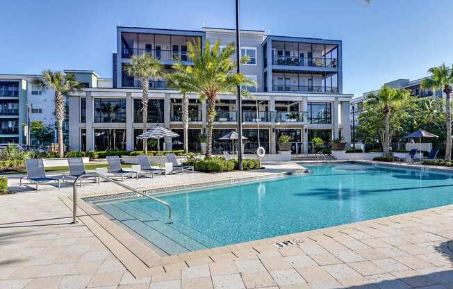 a swimming pool in front of a building with palm trees