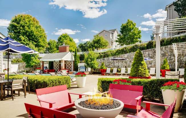 a patio with red chairs and tables and a fire pit at Residences at Stevens Pond, Massachusetts, 01906