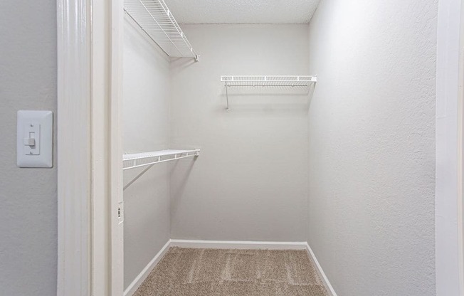a spacious walk in closet in a white room with shelves
