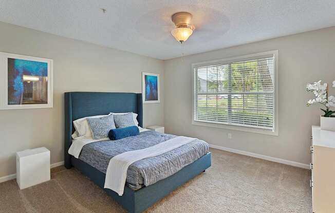 A bedroom with a large bed and a window with blinds.