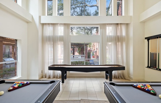 a game room with a pool table and ping pong table in front of a large window