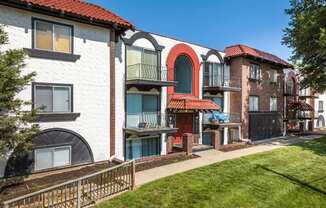 A white building with a red roof and a balcony with a blue curtain.