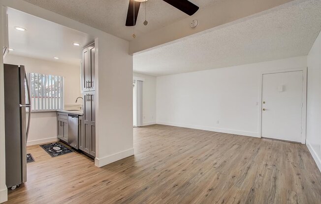 an empty living room with a kitchen in the background
