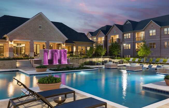 a swimming pool with lounge chairs and a fountain in front of an apartment building
