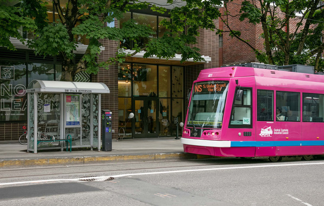 a pink bus is parked on the side of a street