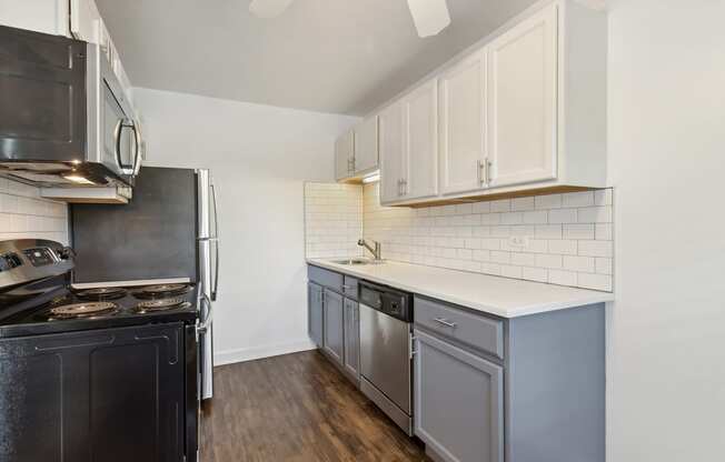 a kitchen with white cabinets and black appliances at The Hinsdale, Hinsdale, Illinois