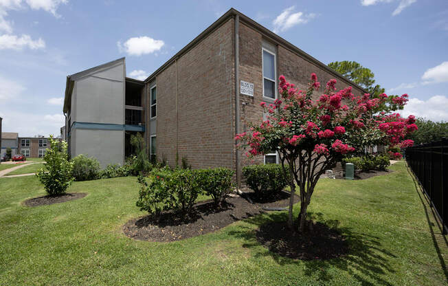 A brick building with a tree with pink flowers in front of it.
