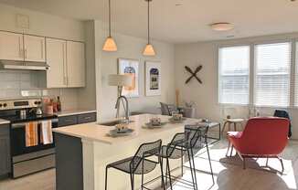 Model apartment kitchen with overhead lights, white counters and breakfast bar