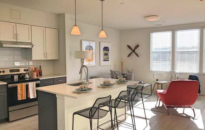 Model apartment kitchen with overhead lights, white counters and breakfast bar