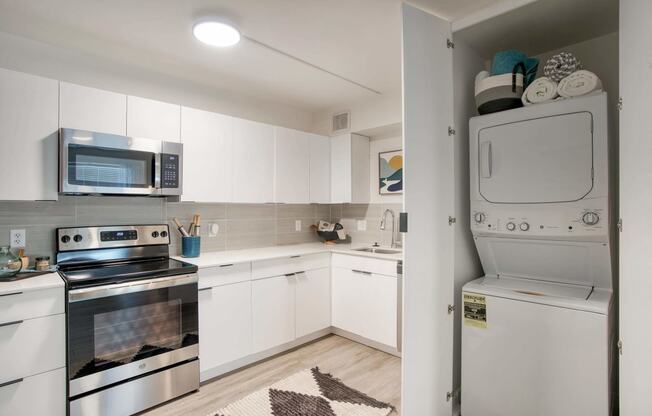 a white kitchen with stainless steel appliances and white cabinets at Presidio Palms Apartments, Arizona