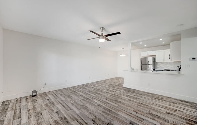 A room with a ceiling fan and wooden flooring.
