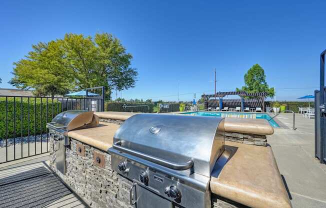 BBQ Picnic Area with Grills and View of Lounge Chairs and Pool at Silverstone Apartments, Davis, California