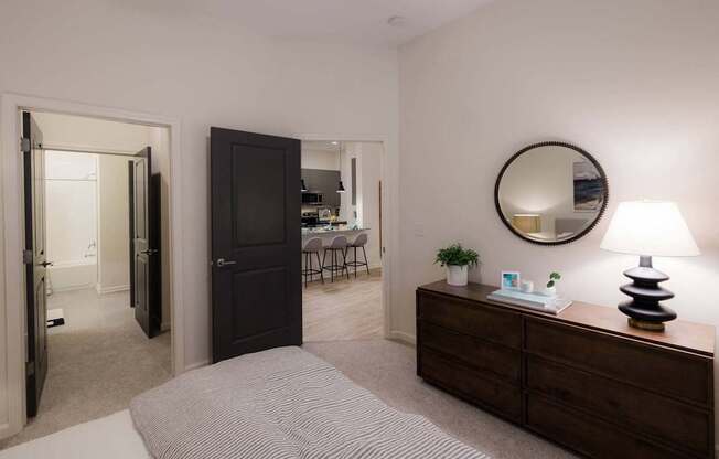 A bedroom with a bed, dresser, mirror, and lamp.