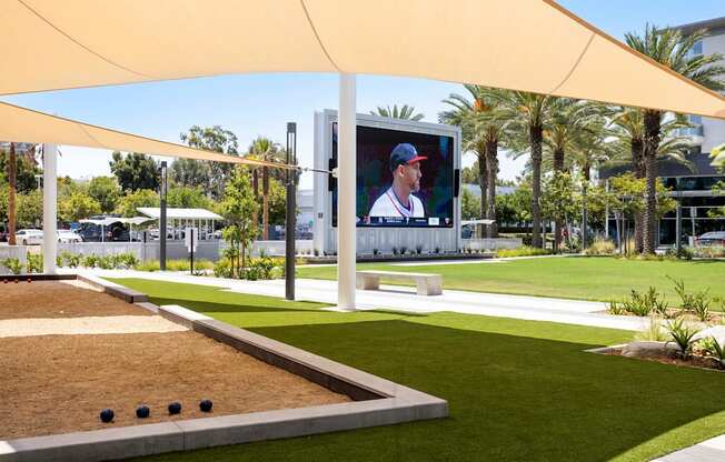 A large screen is set up outside with a baseball game on it. at Elements Apartments*, California, 92612