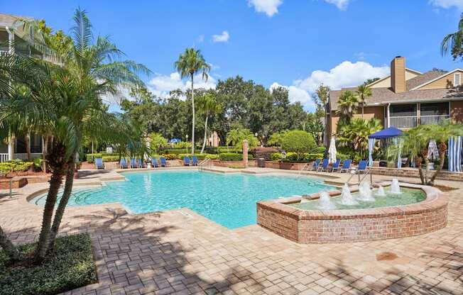 A pool with a fountain in the middle of a brick patio.