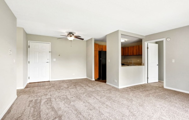 an empty living room with carpet and a ceiling fan