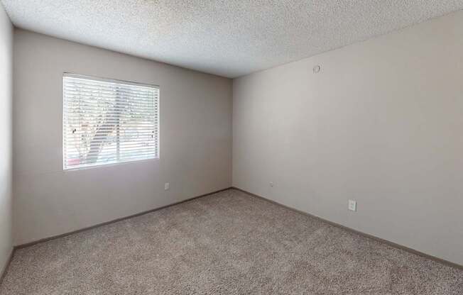 A room with a window covered by white blinds.
