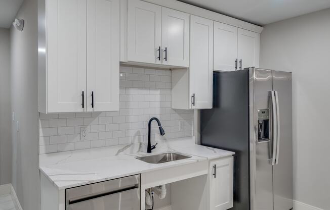 a kitchen with white cabinets and a stainless steel refrigerator