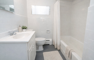 A white bathroom with a toilet, sink, and bathtub.