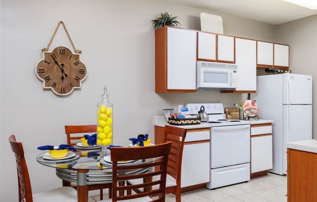 a dining area with a table and chairs and a kitchen in the background