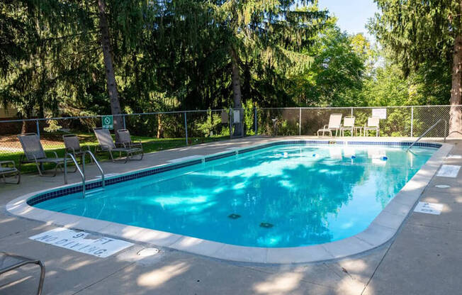 a swimming pool with chairs and a fence around it