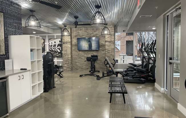 a gym with weights machines and a tv on a brick wall at Edge 35, Indianapolis