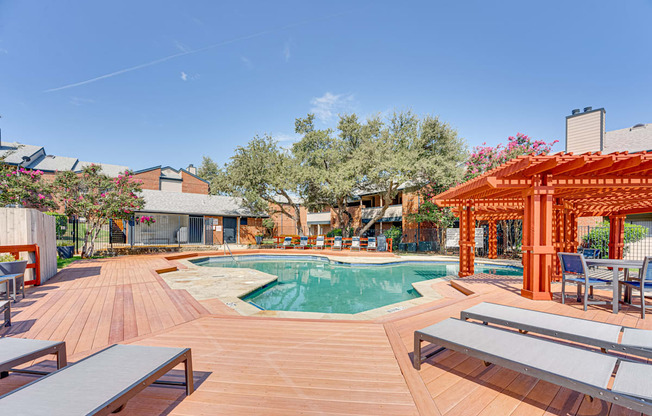 a swimming pool with a wooden deck with tables and chairs