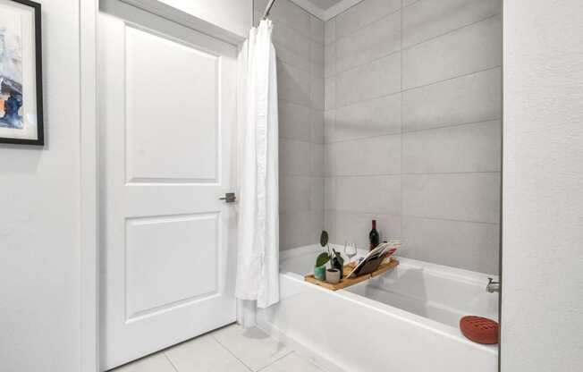 a white bathroom with a tub and a white door