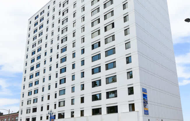 A tall white building with a blue sign on the bottom right.