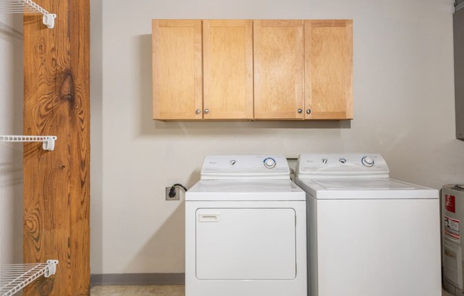 a washer and dryer in a laundry room with wooden cabinets