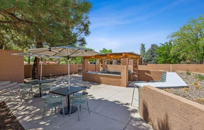 a patio with tables and umbrellas and a jacuzzi at Acacia Gardens, New Mexico