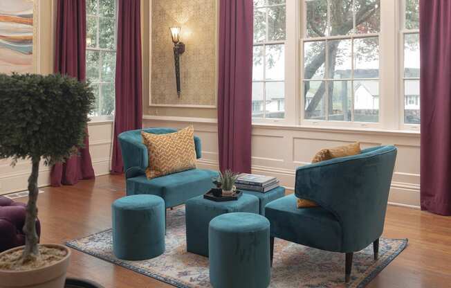 a living room with purple curtains and a blue chair and ottoman