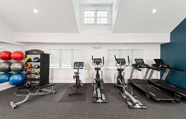 A spacious gym with a variety of exercise equipment including treadmills, stationary bikes, and a rowing machine.