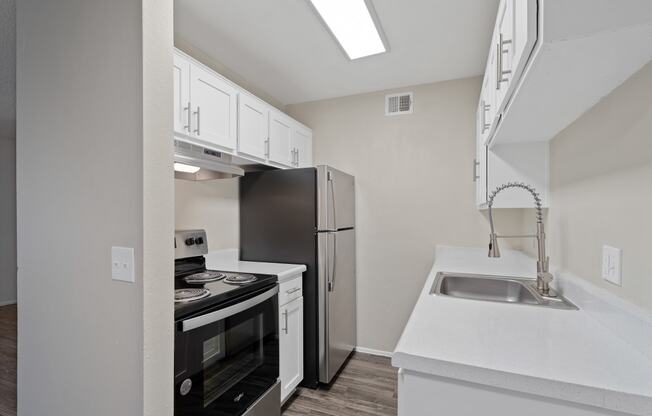 Kitchen with white cabinets and black appliances and a stainless steel refrigerator at Agave Apartments, Tucson, Arizona