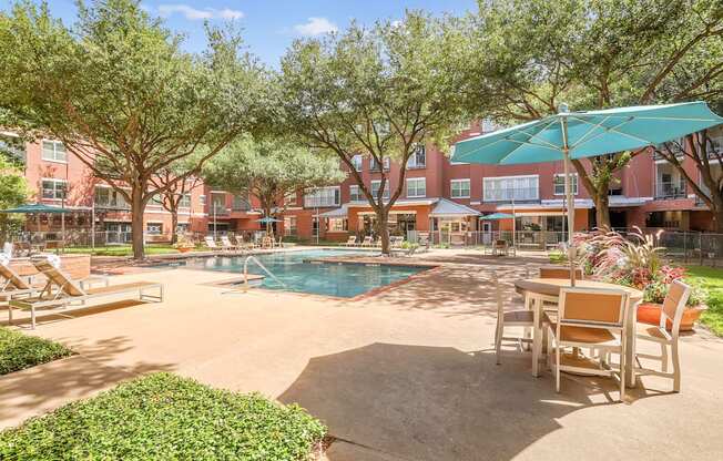 A pool surrounded by chairs and trees.