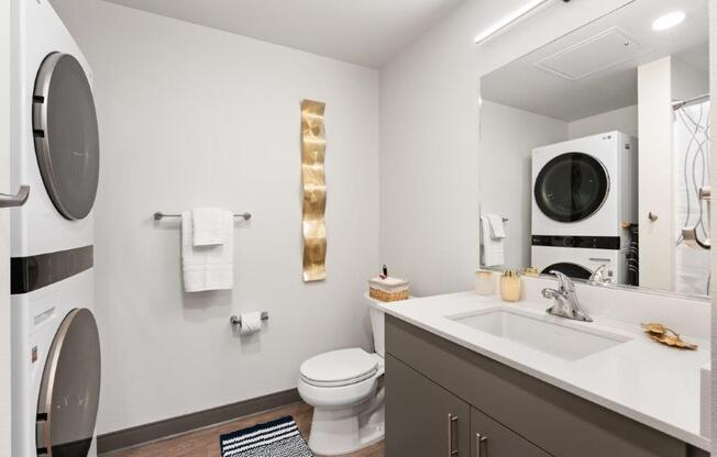 A modern bathroom with a toilet, sink, mirror, and towel rack.
