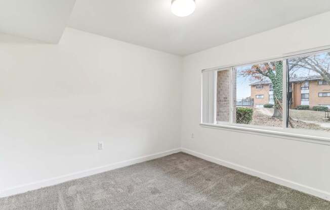 an empty living room with a large window and carpet