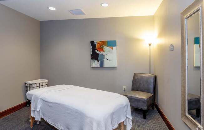 A bedroom with a bed, chair, and painting on the wall.