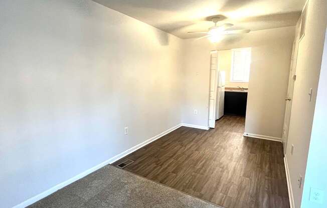 an empty living room with wood flooring and a ceiling fan