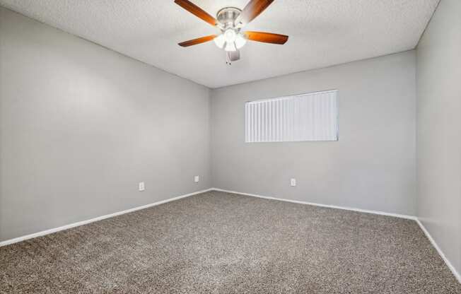 the spacious living room with ceiling fan and carpeting